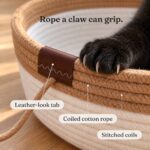 cotton-rope-cat-basket-details-close-up Close-up of a black cat's claws in the caramel rope rim, labeled leather-look tab, coiled cotton rope and stitched coils