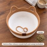 snugweave-rope-cat-basket-whats-included Flat lay on a dining table: a caramel rope cat basket bed with the rope ball, loose dried catnip and a coffee mug